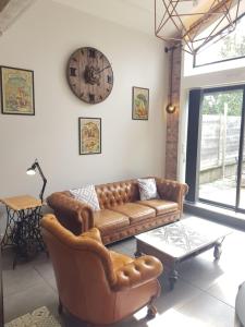 salon z kanapą i zegarem na ścianie w obiekcie spacieuse maison de ville avec espace détente w mieście Rezé