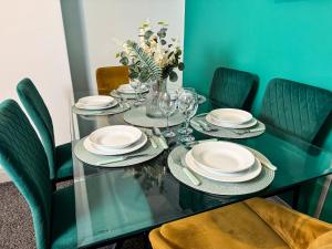 a green table with plates and glasses and chairs at Hambledon House 4BR Entire Home in Middlesbrough