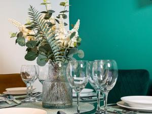 a table with wine glasses and a vase with flowers at Hambledon House 4BR Entire Home in Middlesbrough