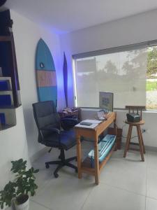 a office with a desk and a chair and a surfboard at Pousada Kasarão Praia Grande Ubatuba in Ubatuba