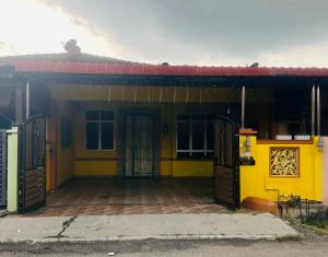 a yellow house with two doors and a porch at Homestay Bukit Katil Damai 2 in Ayer Keroh
