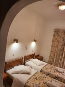 two twin beds in a room with an arch at Panorama Hotel in Agios Stefanos