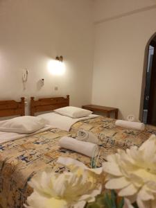 two twin beds in a room with flowers on the floor at Panorama Hotel in Agios Stefanos +5 photos