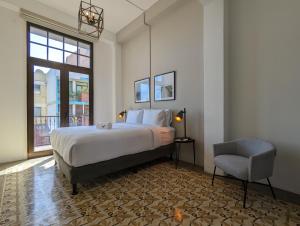 ein Schlafzimmer mit einem Bett und einem Stuhl und einem Fenster in der Unterkunft Donovan By Wynwood House in Panama-Stadt