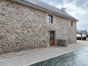 a brick building with a wooden door and water at 2 gîtes à la campagne, proche mer, 18 personnes in Landévant