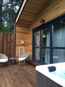 a wooden deck with chairs and a table and a window at Bakony Deep Forest Vendégház in Bakonyszentlászló