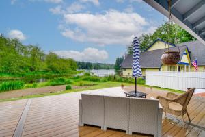 a deck with a view of a river and a house at Lakefront Bremerton Vacation Rental with Hot Tub! in Brinnon