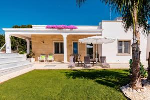 a white house with a lawn and an umbrella at B&B Villa Noemi in Porto Cesareo
