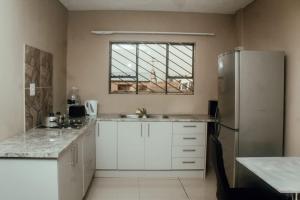 a kitchen with white cabinets and a refrigerator at Kwadines Accommodation in Standerton