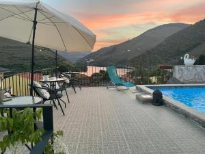 a pool with tables and chairs and an umbrella at Casa Nunes in Pinhão