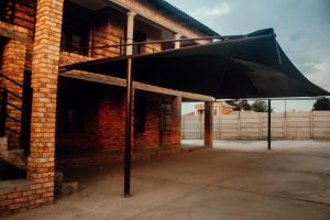 a large black umbrella in front of a brick building at Kwadines Accommodation in Standerton