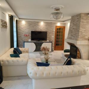 a living room with two white couches and a fireplace at Magnifique villa au cœur de la nature in Marigny-en-Orxois
