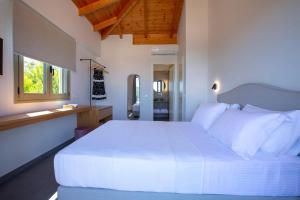 een slaapkamer met een groot wit bed en een raam bij Veramente Villas With Sea view in Lefkada