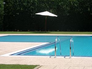 an empty swimming pool with an umbrella and an umbrella at Hotel Rural Aldeaduero in Saucelle