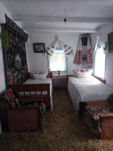 a bedroom with two beds and a chair and windows at Дибинецькі Карпати in Dybintsy