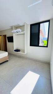 a white room with a tv and a window at Casa Samambaia in Goiânia