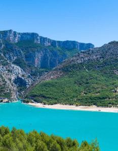 Una vista de un lago azul con montañas al fondo. en MOBIL HOME DANS CAMPING 3 etoiles GORGES DU VERDON CALME 4 PERS PLANCHA, en Sainte-Croix-du-Verdon