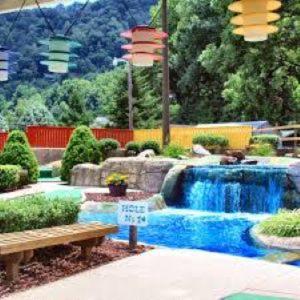 a swimming pool with a waterfall and a bench at Halfback Ridge-heart of Maggie Valley-hot tub-fenced pet area-gazebo-views in Maggie Valley