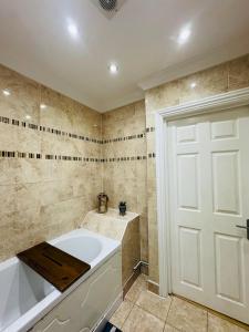 a bathroom with a tub and a white door at Charming 2 Bedroom Flat with Urban Views in Romford +23 photos