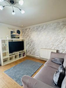 a living room with a couch and a tv at Charming 2 Bedroom Flat with Urban Views in Romford