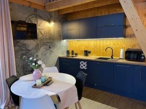 a kitchen with a white table and blue cabinets at Stodoła Sople - domek z balią in Sople