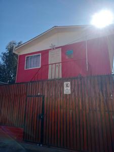 a red and white house with a fence and a gate at Hostal Manuel Bugueño in El Cerrillo