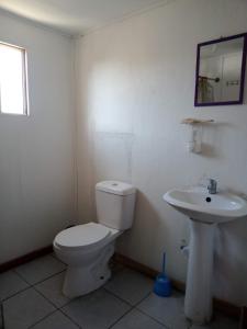 a white bathroom with a toilet and a sink at Hostal Manuel Bugueño in El Cerrillo