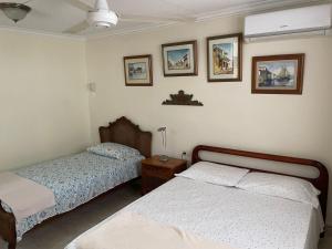 a bedroom with two beds and pictures on the wall at Casa Estela in Cartagena de Indias