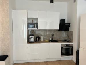 a white kitchen with white cabinets and appliances at Double Rest Agat in Jastrzębia Góra