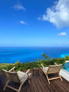 two chairs and a table on a deck with the ocean at SECRET HILL in Athani
