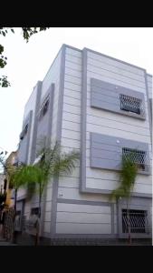ein weißes Gebäude mit Fenstern und einer Palme davor in der Unterkunft Appartement cosy 1er étage in Kenitra