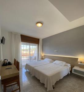 a bedroom with a bed and a desk and a window at Hotel Riveiro II in Sanxenxo