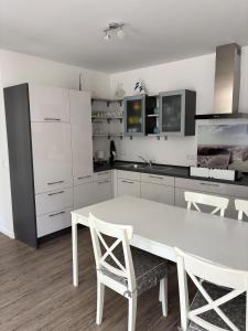 a white kitchen with a white table and chairs at V Gartenpalais Wohnung 1 in Norderney