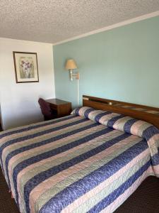 a bed in a hotel room with a striped bedspread at Royal Inn in Oklahoma City