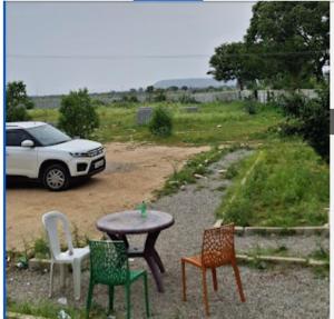 une table, des chaises et une voiture dans une allée dans l'établissement SPR Sri Prathapa Rudra Cottages, à Manānūr