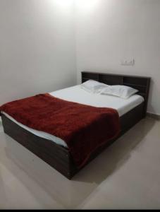 Ce lit se trouve dans un dortoir blanc doté d'une couverture rouge. dans l'établissement SPR Sri Prathapa Rudra Cottages, à Manānūr