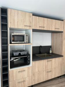 a kitchen with wooden cabinets with a microwave and a sink at Appartement T2 Neuf Cosy et charmant in Briançon
