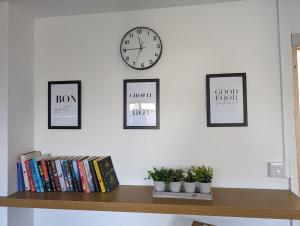 ein Regal mit vier Bildern und einer Uhr an einer Wand in der Unterkunft Family house near the beach! in Saint Columb Minor