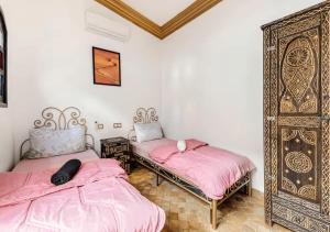 two beds in a room with pink sheets at 16 Riads in Marrakesh