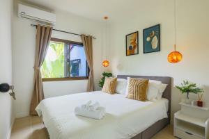 a bedroom with a large bed with two towels on it at Wink Garden 3 Bedrooms Bangtao Beach Phuket in Ban Thalat Choeng Thale