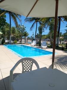 a swimming pool with a table and chairs and an umbrella at Pousada Vivenda Da Praia in Prado