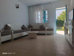 ein Wohnzimmer mit Sofas, Tisch und Fernseher in der Unterkunft Moha in Kelibia