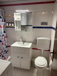 a bathroom with a white toilet and a sink at Sani Garden House in Sani Beach