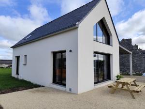 une maison blanche avec des fenêtres noires et une table de pique-nique dans l'établissement Le Pélican By Nid'Ouest, à Plovan