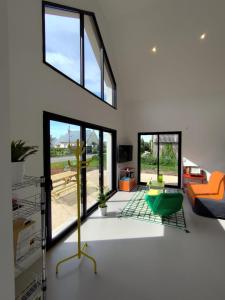 - un salon avec de grandes fenêtres et une chaise verte dans l'établissement Le Pélican By Nid'Ouest, à Plovan