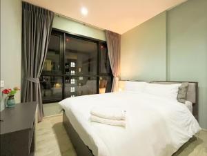 a bedroom with a large white bed and a window at The Base Prime in Pattaya Central