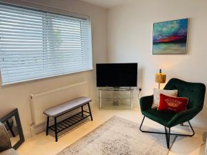 a living room with a green chair and a flat screen tv at Modern, Tiny Home, Beach Retreat in Southerndown