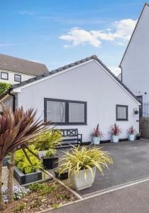 a white house with potted plants in front of it at Modern, Tiny Home, Beach Retreat in Southerndown