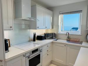 a kitchen with white cabinets and a sink and a window at Modern, Tiny Home, Beach Retreat in Southerndown