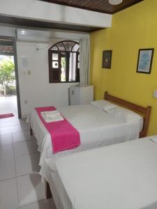 two beds in a room with yellow walls at Pousada Vivenda Da Praia in Prado